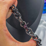 Silver chain bracelet held by a hand against a blurred background